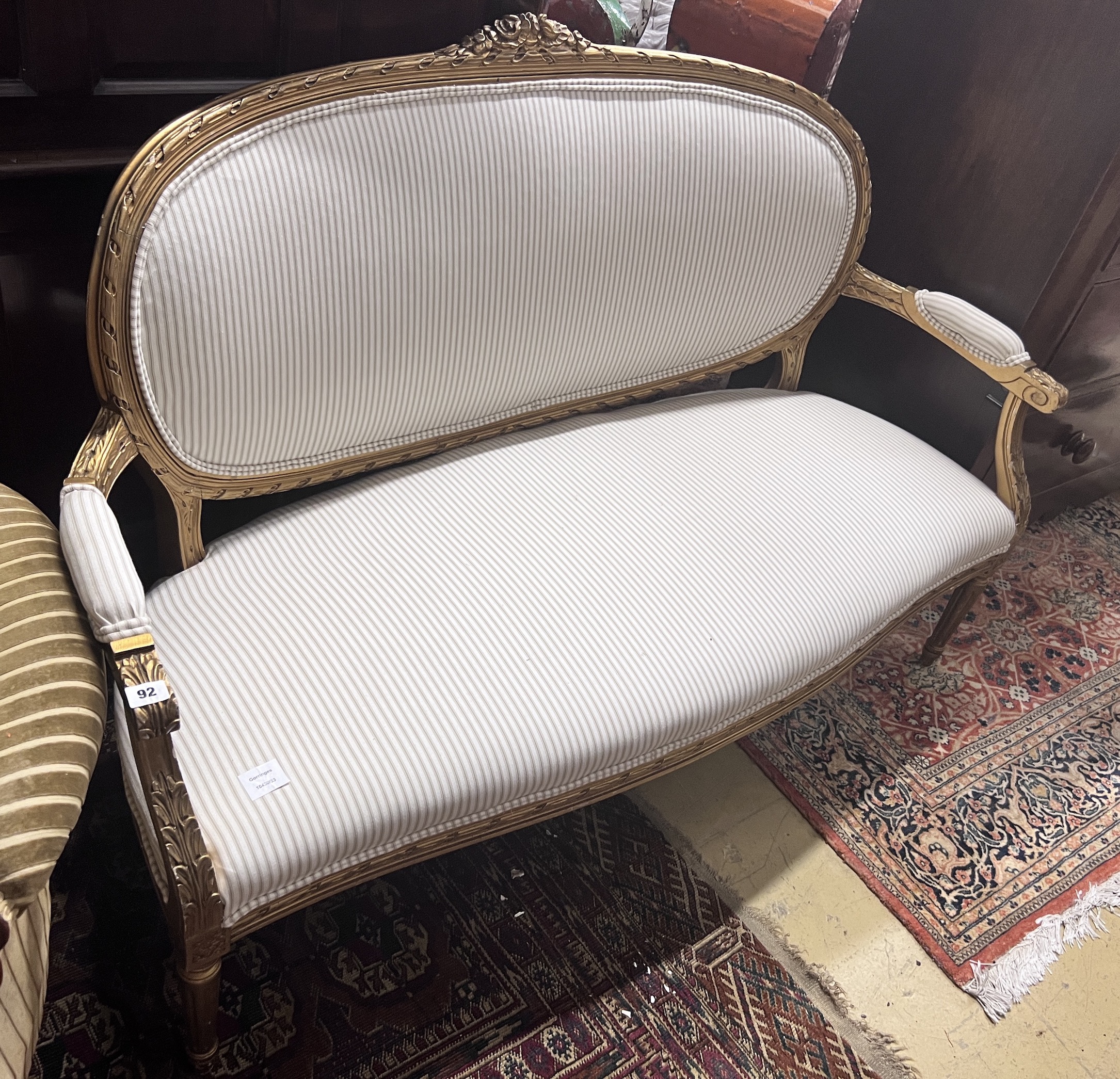 A French giltwood and composition settee, recently re-upholstered in a striped linen fabric, width 140cm, depth 60cm, height 92cm